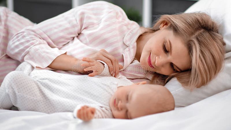 Gelukkige moeder bewondert een schattige slaapbaby die samen op bed ligt. Foto van de camera van de rode 4.000 film