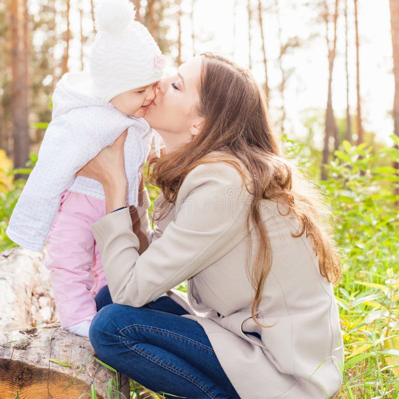 Gelukkige moeder die haar baby kussen bij openlucht, de herfstpark stock afbeelding Gelukkige moeder die haar baby kussen bij openlucht, de herfstpark stock afbeelding