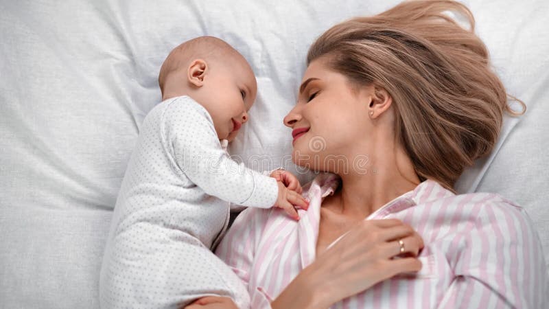 Gelukkige moeder en baby die op bed liggen voelen zich samen liefde en tederheid. middelschot op rode camera