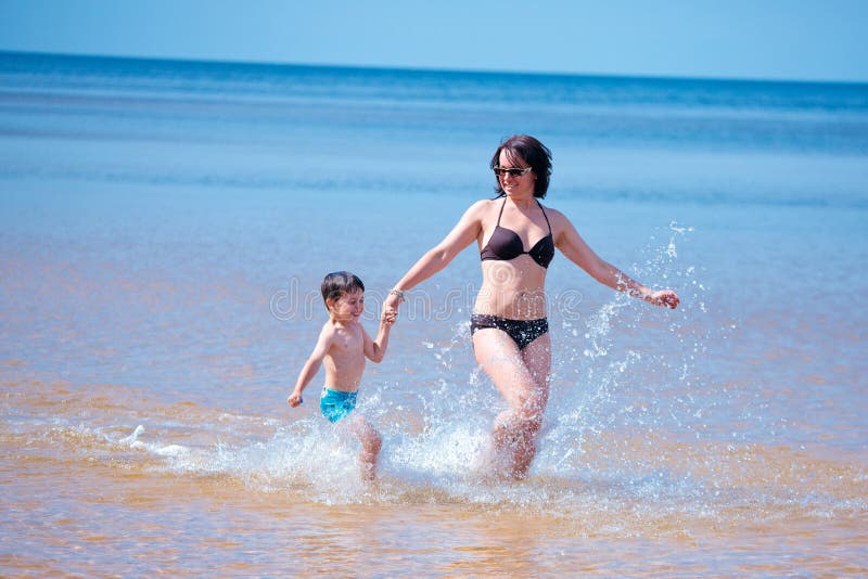 Gelukkige moeder en haar weinig zoon bij het strand royalty-vrije stock foto's Gelukkige moeder en haar weinig zoon bij het strand royalty-vrije stock foto's