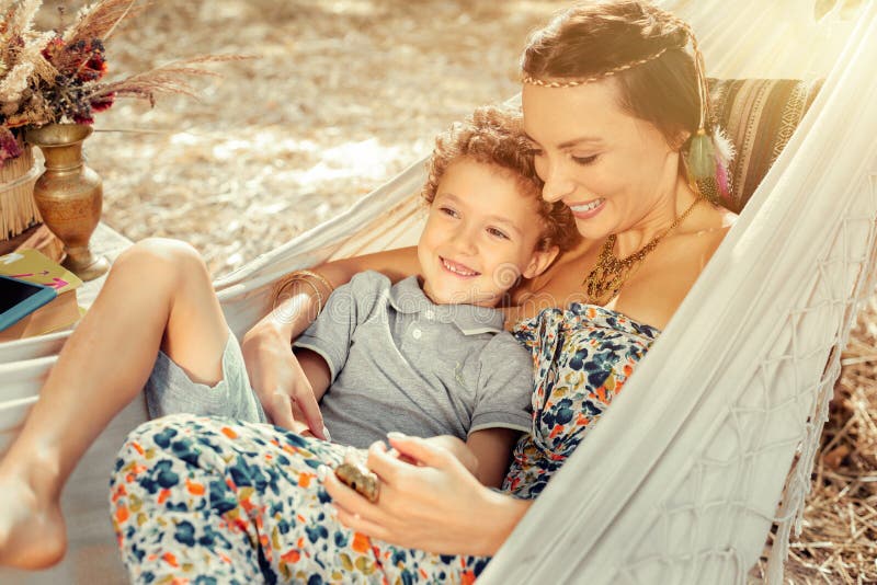 Gelukkige mooie vrouw die in hangmat met haar zoon liggen royalty-vrije stock afbeelding Gelukkige mooie vrouw die in hangmat met haar zoon liggen royalty-vrije stock afbeelding