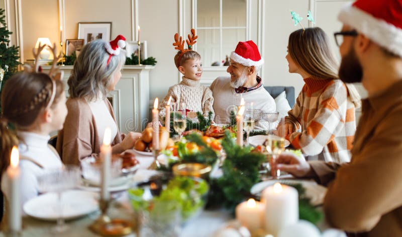 Gelukkige multi - generatiefamilie in santa hats tijdens de maantafel die toasts ( xmas ) en klinkbrillen vertelt