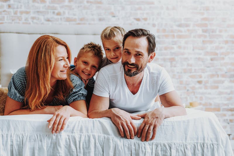 Gelukkige ouders die op bed met jonge geitjes leggen royalty-vrije stock fotografie Gelukkige ouders die op bed met jonge geitjes leggen royalty-vrije stock fotografie