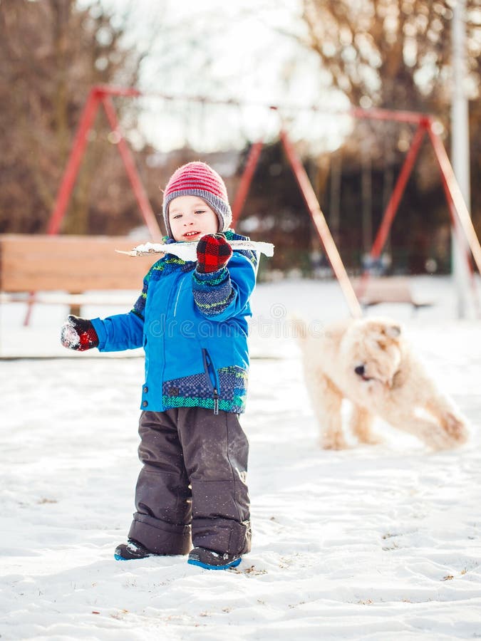 Gelukkige peuter witte Kaukasische jongen die en met sneeuw en witte grote grote huisdierenhond lopen spelen stock fotografie Gelukkige peuter witte Kaukasische jongen die en met sneeuw en witte grote grote huisdierenhond lopen spelen stock fotografie