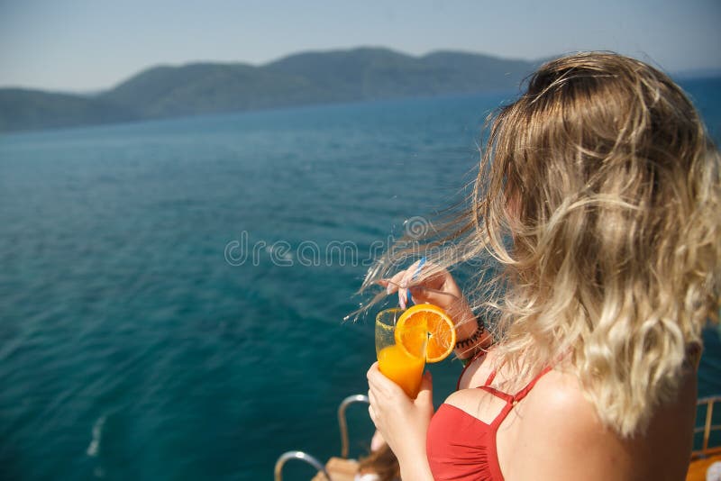 Gelukkige rondborstige vrouw op jacht Dame in meisje in de holdings oranje verse drank van de koraalbikini Koele drank en verse a