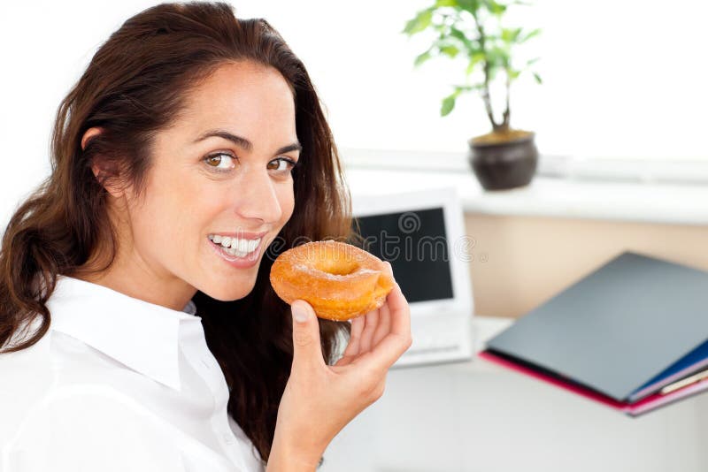 Gelukkige Spaanse onderneemster die een doughnut eet royalty-vrije stock afbeelding Gelukkige Spaanse onderneemster die een doughnut eet royalty-vrije stock afbeelding
