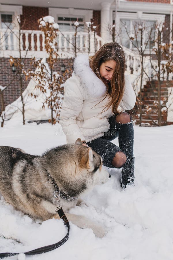 Gelukkige speelse tijd van opgewekte blije jonge vrouw die pret met schor hond op de straat in sneeuw hebben Gelukkige de wintert royalty-vrije stock afbeeldingen Gelukkige speelse tijd van opgewekte blije jonge vrouw die pret met schor hond op de straat in sneeuw hebben Gelukkige de wintert royalty-vrije stock afbeeldingen