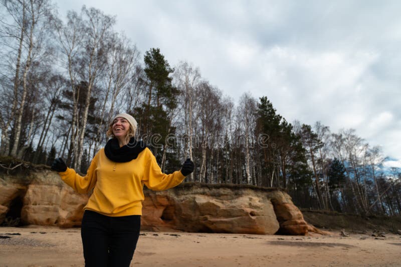 Gelukkige sport en manierminnaarenthousiast die op een strand uitwerken die heldere gele sweater en zwarte handschoenen en een GL stock afbeelding Gelukkige sport en manierminnaarenthousiast die op een strand uitwerken die heldere gele sweater en zwarte handschoenen en een GL stock afbeelding