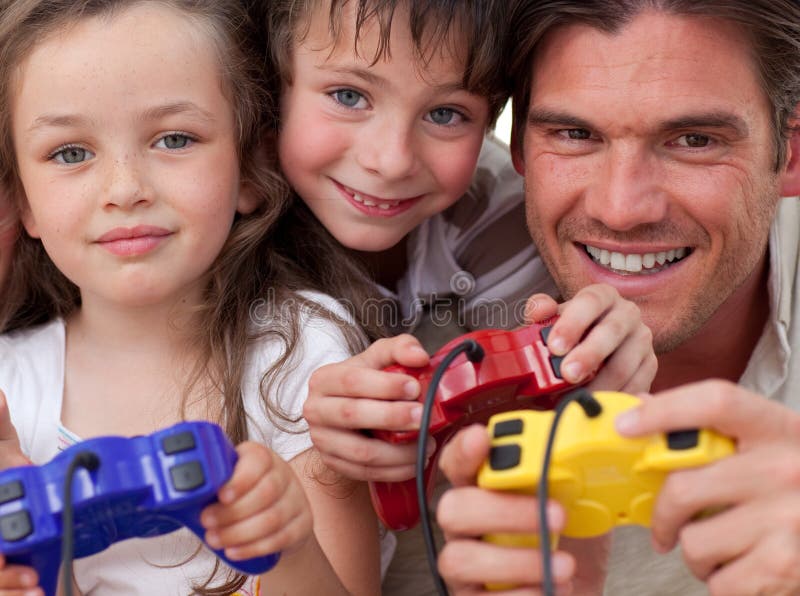 Gelukkige vader en zijn kinderen die videospelletjes spelen stock foto's Gelukkige vader en zijn kinderen die videospelletjes spelen stock foto's