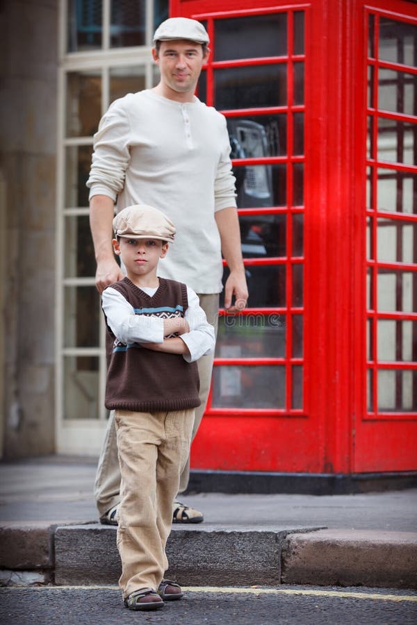 Gelukkige vader en zoon in openlucht door rode telefooncel royalty-vrije stock foto Gelukkige vader en zoon in openlucht door rode telefooncel royalty-vrije stock foto