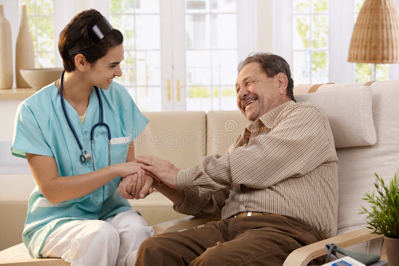 Happy nurse holding hands of elderly patient sitting side by side at home, laughing. Happy nurse holding hands of elderly patient sitting side by side at home, laughing.