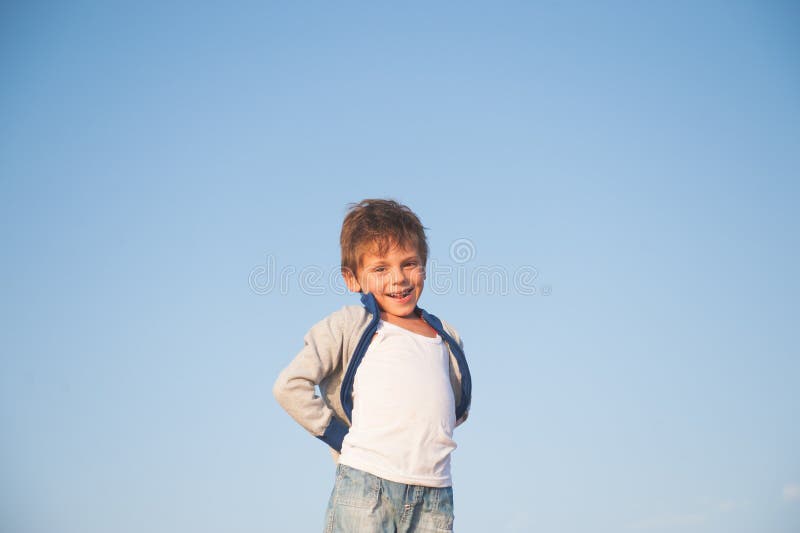 Gelukkige verrukkelijk glimlachend weinig jongen in sweater op blauwe hemelachtergrond stock foto Gelukkige verrukkelijk glimlachend weinig jongen in sweater op blauwe hemelachtergrond stock foto