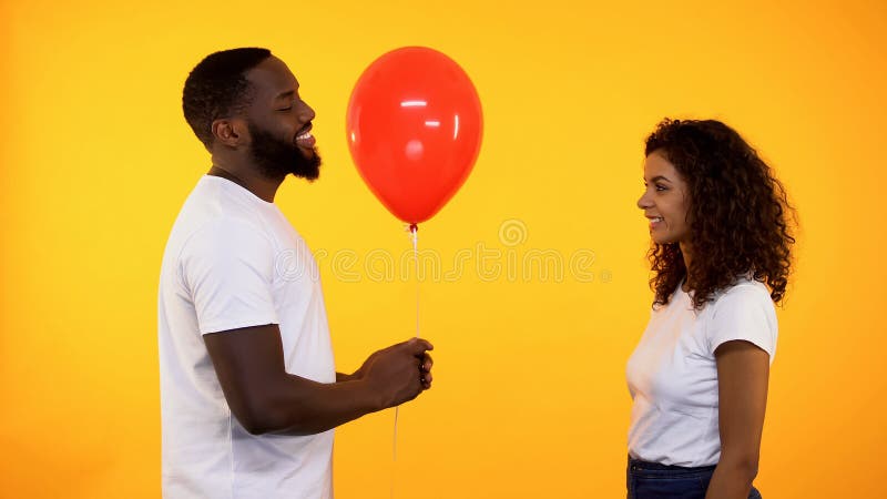 Gelukkige vriend die rode ballon geven aan meisje op oranje achtergrond, datum stock foto's Gelukkige vriend die rode ballon geven aan meisje op oranje achtergrond, datum stock foto's
