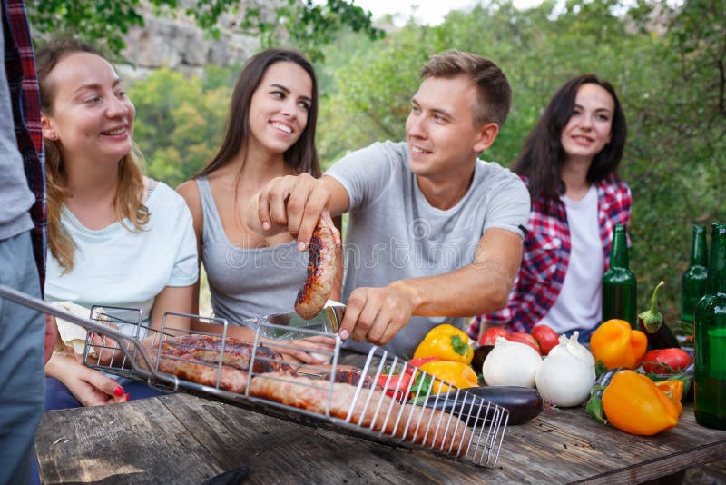 Gelukkige vrienden in het park die picknick op een zonnige dag hebben Groep volwassen mensen die pret op een de zomerpicknick heb royalty-vrije stock fotografie Gelukkige vrienden in het park die picknick op een zonnige dag hebben Groep volwassen mensen die pret op een de zomerpicknick heb royalty-vrije stock fotografie