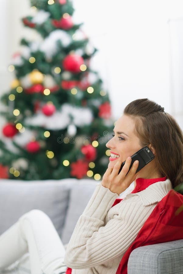 Gelukkige vrouw die dichtbij Kerstboom telefoongesprek maakt stock afbeeldingen Gelukkige vrouw die dichtbij Kerstboom telefoongesprek maakt stock afbeeldingen