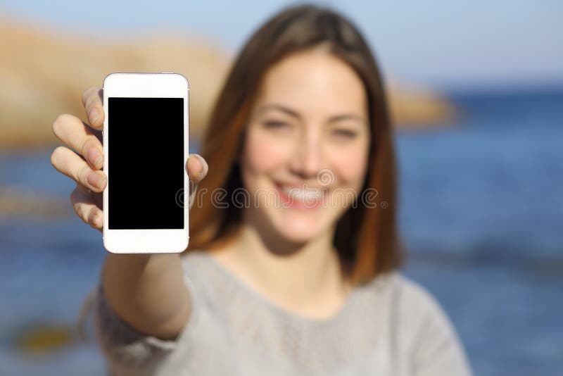 Gelukkige vrouw die een slimme telefoonvertoning op het strand tonen royalty-vrije stock foto's Gelukkige vrouw die een slimme telefoonvertoning op het strand tonen royalty-vrije stock foto's