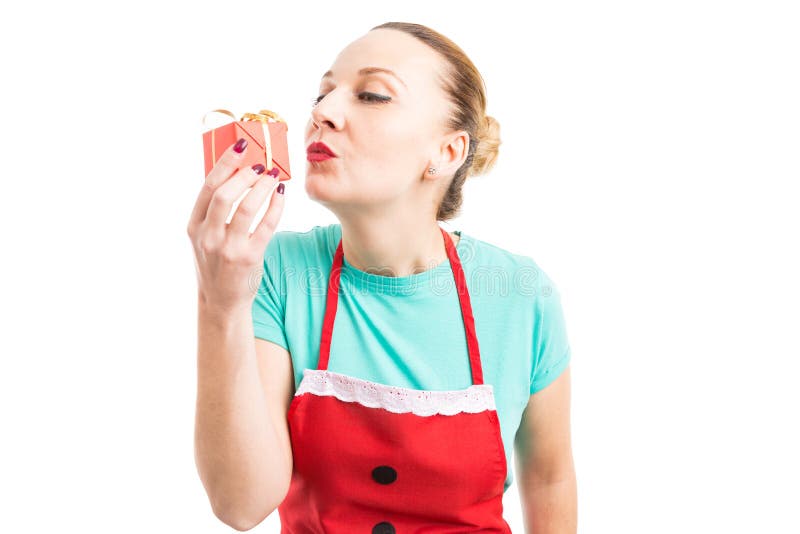 Gelukkige vrouw die rode schort dragen en gift of heden kussen stock afbeelding Gelukkige vrouw die rode schort dragen en gift of heden kussen stock afbeelding