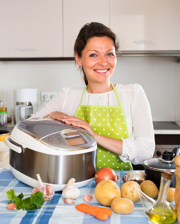 Gelukkige vrouw die slo-kooktoestel met behulp van stock foto Gelukkige vrouw die slo-kooktoestel met behulp van stock foto