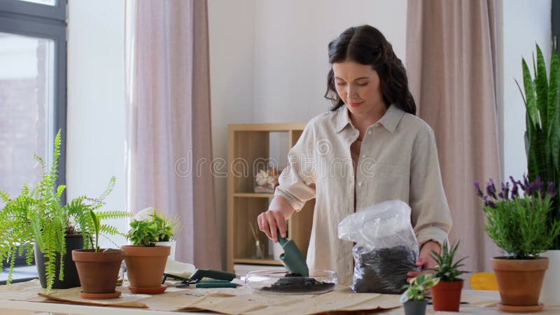 Gelukkige vrouw die thuis bloemen plant