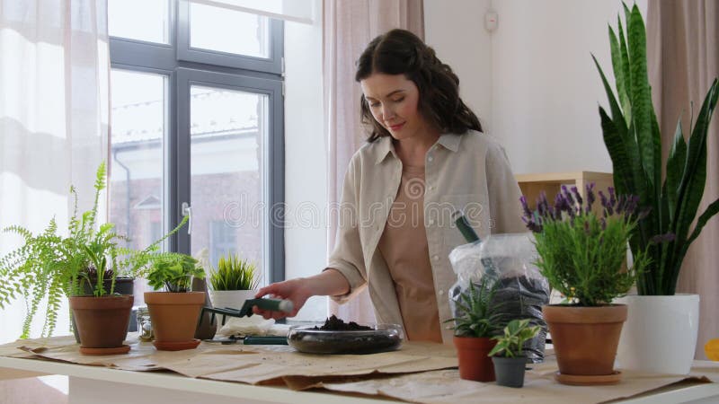 Gelukkige vrouw die thuis bloemen plant