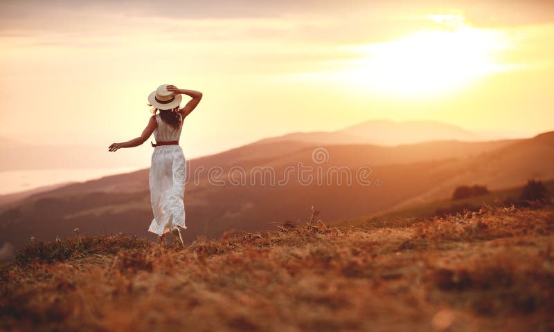 Gelukkige vrouw die zich met haar terug op zonsondergang in aard iwith open handen bevinden royalty-vrije stock foto Gelukkige vrouw die zich met haar terug op zonsondergang in aard iwith open handen bevinden royalty-vrije stock foto