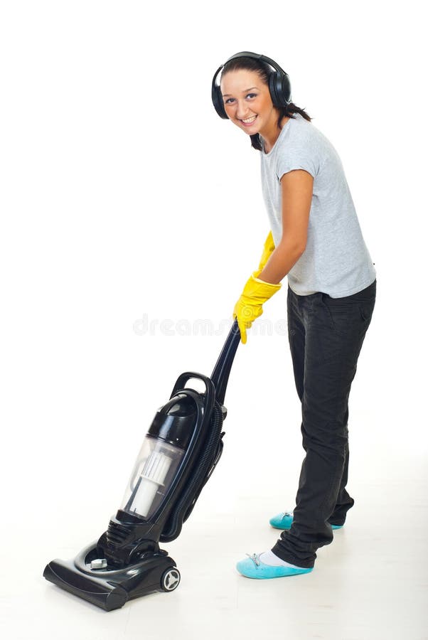Happy woman listening music in headphones and working with vacuum cleaner on white wooden floor. Happy woman listening music in headphones and working with vacuum cleaner on white wooden floor