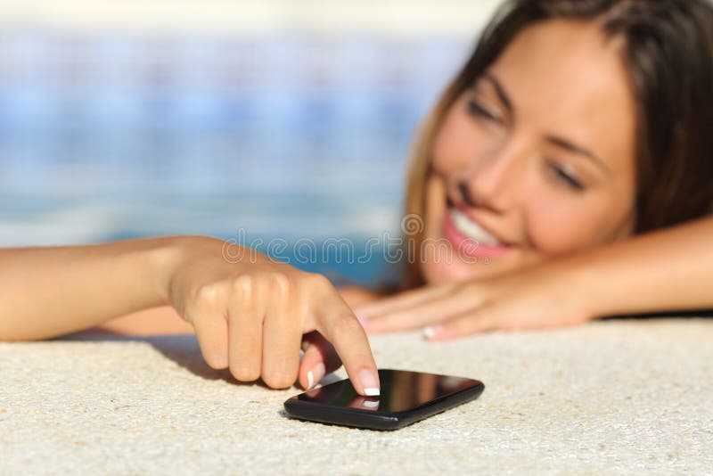 Gelukkige vrouw in vakanties die in het slimme telefoon baden in een zwembad texting stock fotografie Gelukkige vrouw in vakanties die in het slimme telefoon baden in een zwembad texting stock fotografie