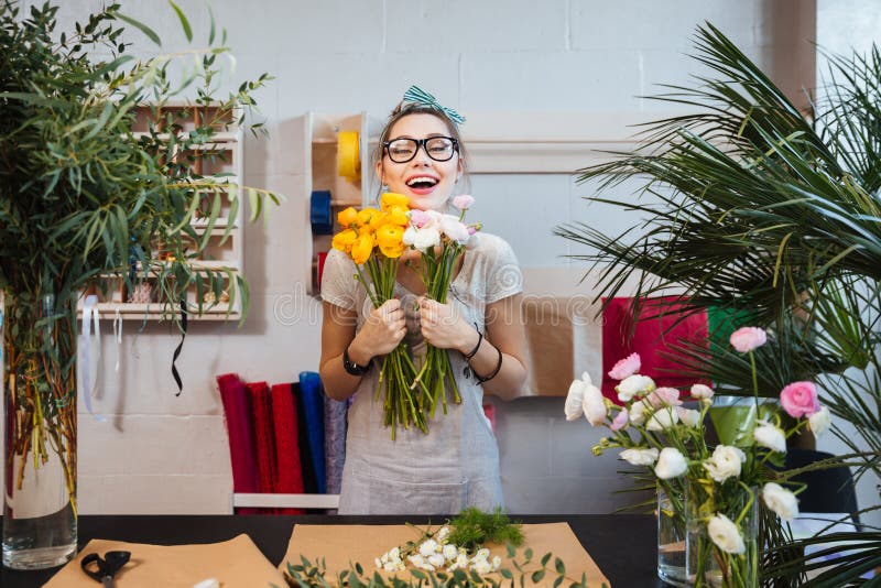 Gelukkige vrouwenbloemist met bos van en bloemen die bevinden zich lachen stock fotografie Gelukkige vrouwenbloemist met bos van en bloemen die bevinden zich lachen stock fotografie