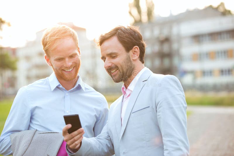 Gelukkige zakenlieden die mobiele telefoon in stad met behulp van stock afbeelding Gelukkige zakenlieden die mobiele telefoon in stad met behulp van stock afbeelding