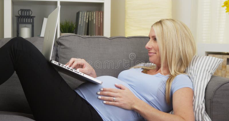Gelukkige zwangere vrouw die op laag liggen die laptop met behulp van royalty-vrije stock fotografie Gelukkige zwangere vrouw die op laag liggen die laptop met behulp van royalty-vrije stock fotografie