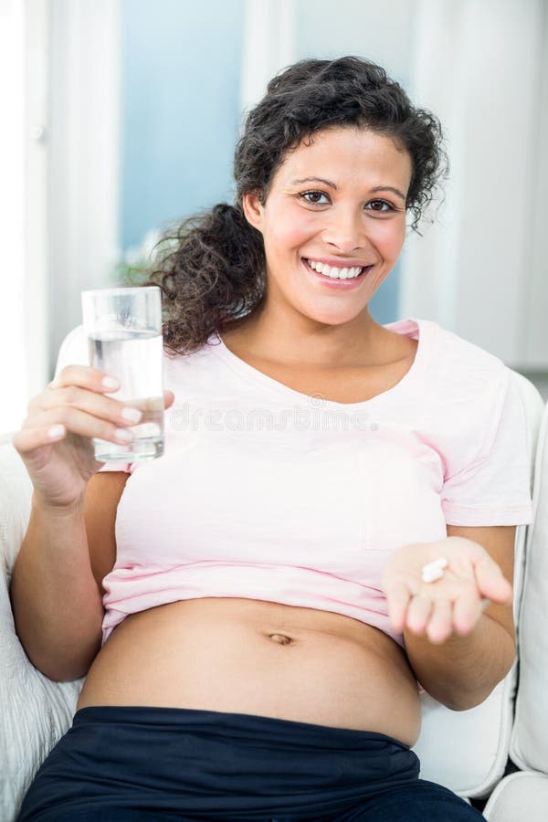 Gelukkige zwangere vrouw die pil thuis nemen royalty-vrije stock foto's Gelukkige zwangere vrouw die pil thuis nemen royalty-vrije stock foto's