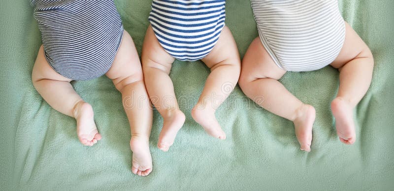 Newborn triplets lie on a stomach on a blanket. Newborn triplets lie on a stomach on a blanket