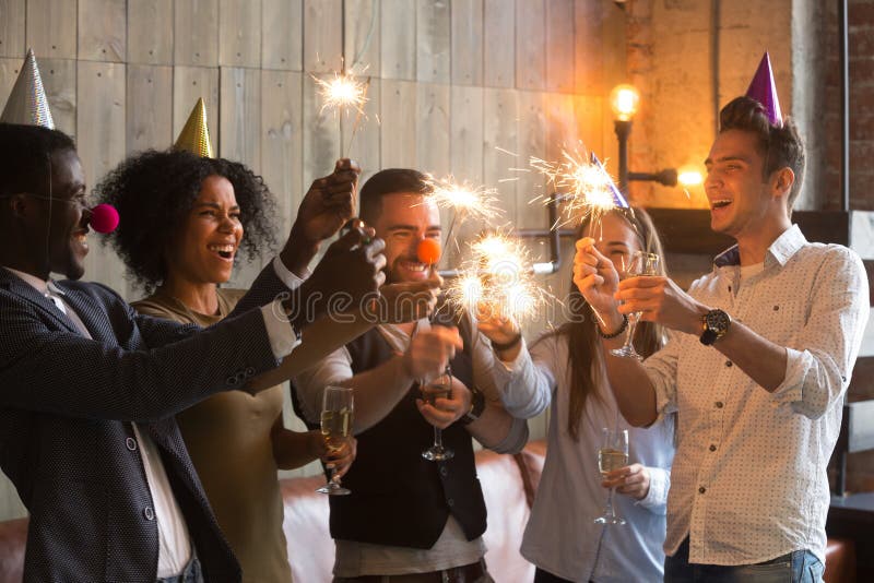 Gemischtrassige Freunde, welche die Wunderkerzegläser, toget feiernd halten lizenzfreie stockfotografie Gemischtrassige Freunde, welche die Wunderkerzegläser, toget feiernd halten lizenzfreie stockfotografie