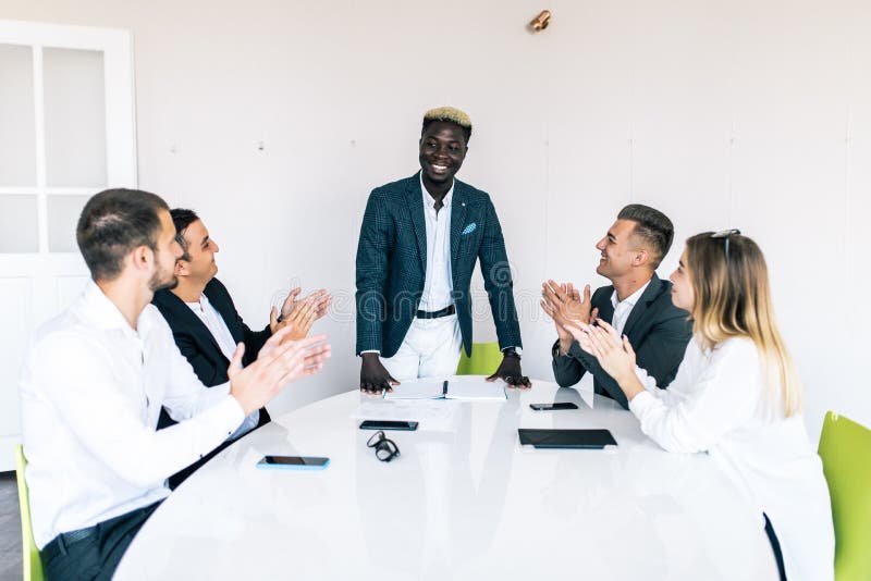 Gemischtrassige Geschäftsleute, die Sitzen am Konferenztische, klatschende Hände des verschiedenen Teams nach Gruppensitzung appl lizenzfreies stockfoto Gemischtrassige Geschäftsleute, die Sitzen am Konferenztische, klatschende Hände des verschiedenen Teams nach Gruppensitzung appl lizenzfreies stockfoto