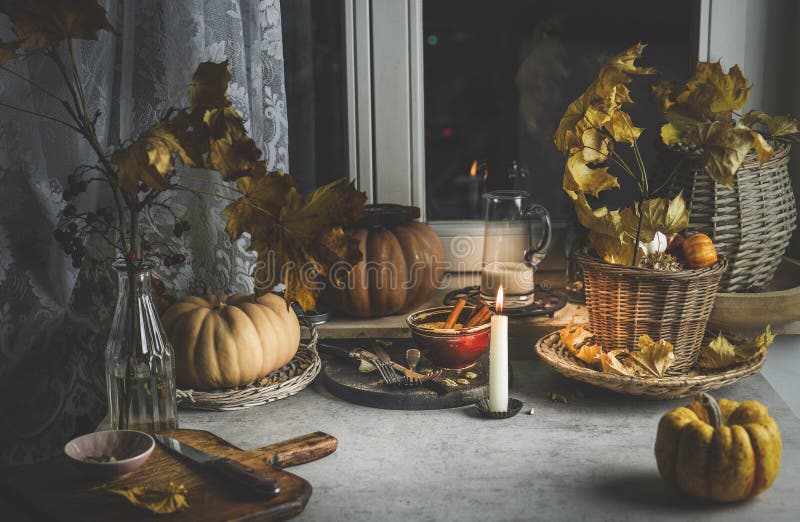 Gemütliche Herbstkuchenunterlage mit Kürbis Herbst Blätter Kerzen Schneidebrett und Küchenutensilien auf grauem Betontisch bei lizenzfreie stockfotos