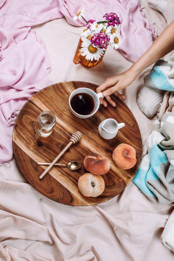 Gemütlicher Herbst oder Winter flatlay vom hölzernen Behälter mit Tasse Kaffee, Pfirsiche, Rahmtopf mit Pflanzenmilch. Gemütlicher Herbst oder Winter flatlay vom hölzernen Behälter mit Tasse Kaffee, Pfirsichen, Rahmtopf mit Pflanzenmilch, Sirup und Löffeln auf Pastellblättern und Frau ` s Hand, selektiver Fokus