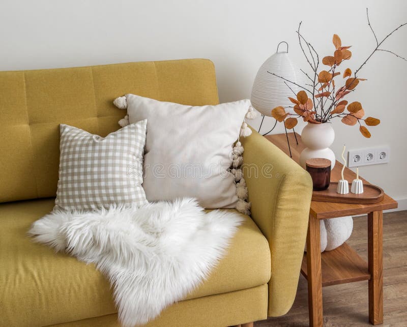 Gemütliches Herbstinnere des Wohnzimmers, ein Sofa mit dekorativen Kissen und ein gepflasterter Herbst hinterlässt eine Bouquetker stockfotos