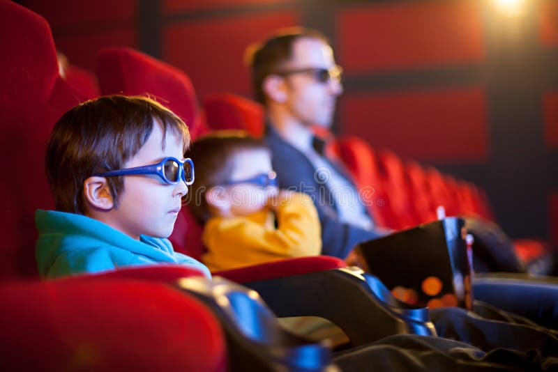 Gene e duas crianças, meninos, olhando o filme dos desenhos animados no cinema fotos de stock Gene e duas crianças, meninos, olhando o filme dos desenhos animados no cinema fotos de stock
