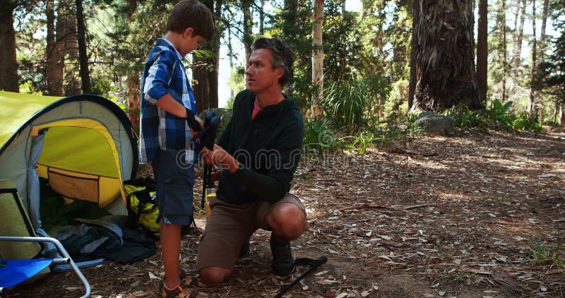 Gene o filho de ensino para usar o polo trekking fora da barraca