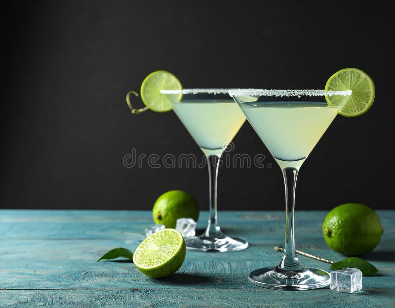 Glasses of Lime Drop Martini cocktail on light blue wooden table against dark background vector illustration