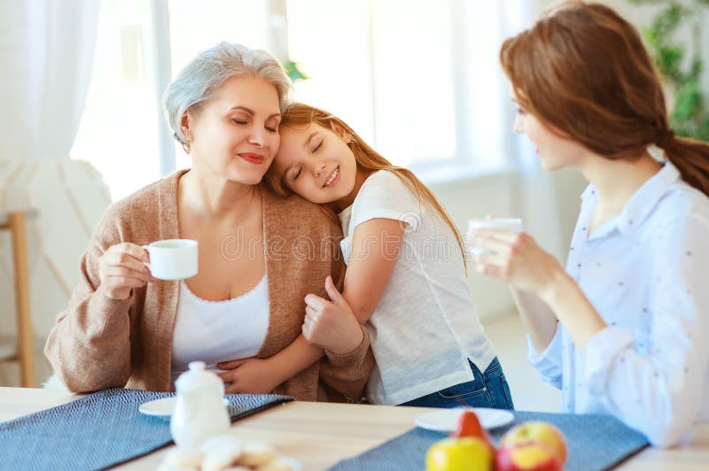 Generazioni nonna, madre e bambino della famiglia tre abbraccianti nella cucina a casa fotografia stock libera da diritti Generazioni nonna, madre e bambino della famiglia tre abbraccianti nella cucina a casa fotografia stock libera da diritti