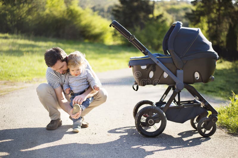Generi con la piccola figlia del bambino e del figlio in passeggiatore Parco soleggiato fotografie stock Generi con la piccola figlia del bambino e del figlio in passeggiatore Parco soleggiato fotografie stock