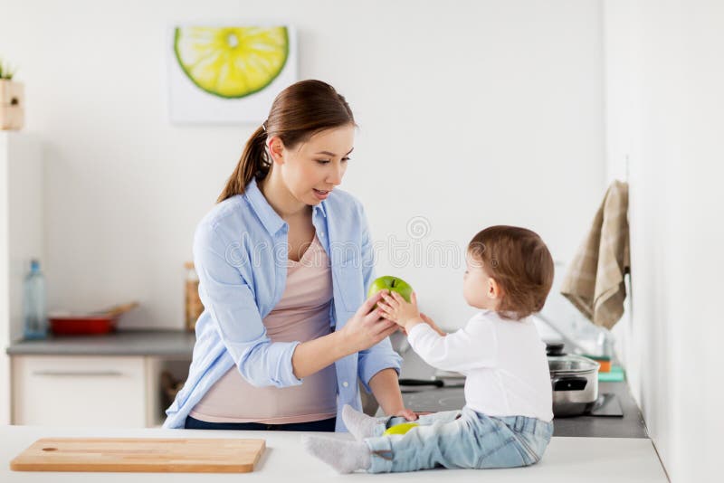 Generi dare la mela verde alla cucina del bambino a casa immagini stock Generi dare la mela verde alla cucina del bambino a casa immagini stock