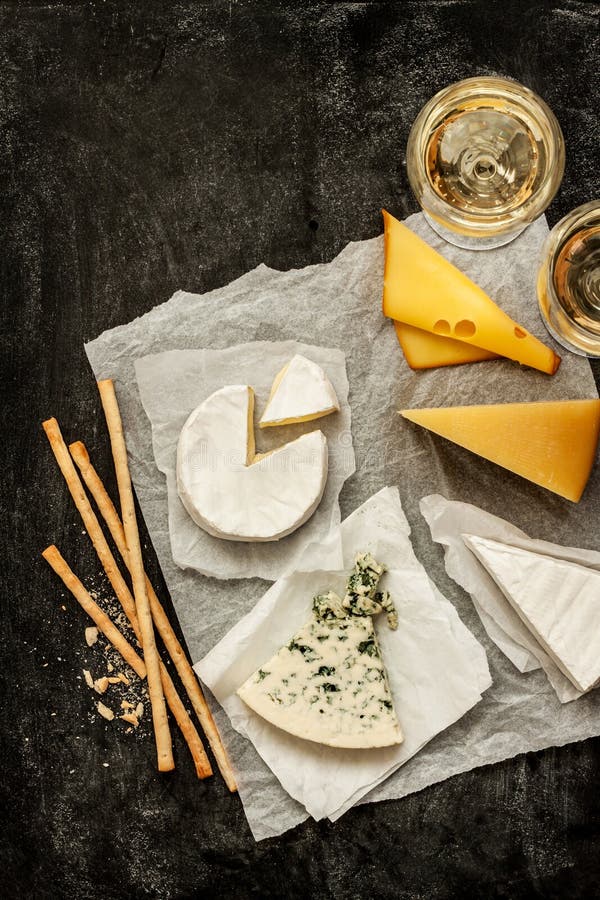 Generi differenti di formaggi, di vino bianco e di spuntini sul nero fotografia stock