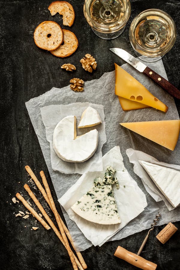 Generi differenti di formaggi, di vino bianco e di spuntini sul nero fotografia stock