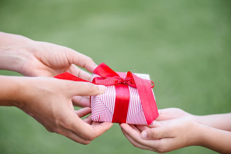 Generi la mano che dà un contenitore di regalo al suo bambino