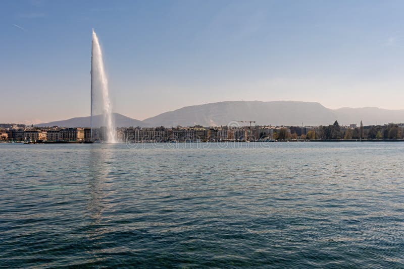 Geneva, Switzerland - April 15, 2019: Beautiful view of the water jet fountain in the lake of Geneva and the cityscape