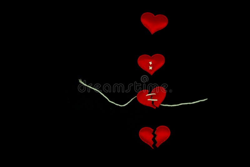 Healing broken heart concept  red heart is sewn with white thread with needle on black background. Healing broken heart concept  red heart is sewn with white thread with needle on black background.