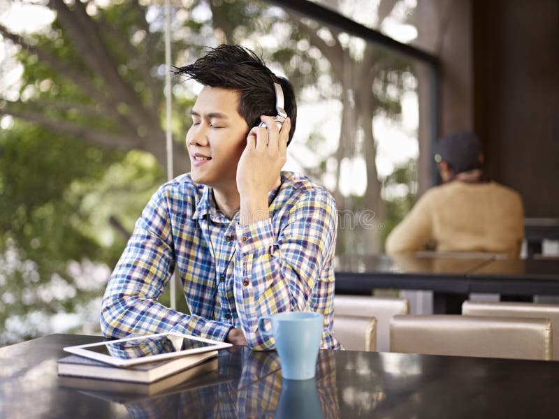 Young men wearing headphone enjoying music in cafe. Young men wearing headphone enjoying music in cafe