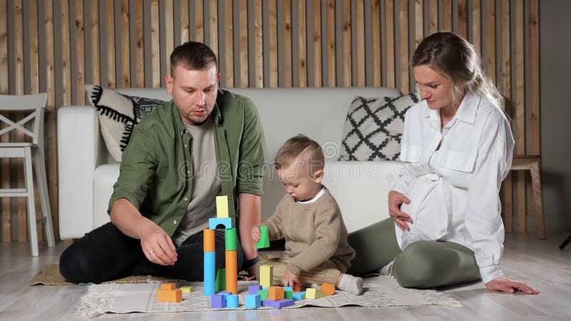 Genitori e figli piccoli giocano con blocchi colorati di legno video d archivio